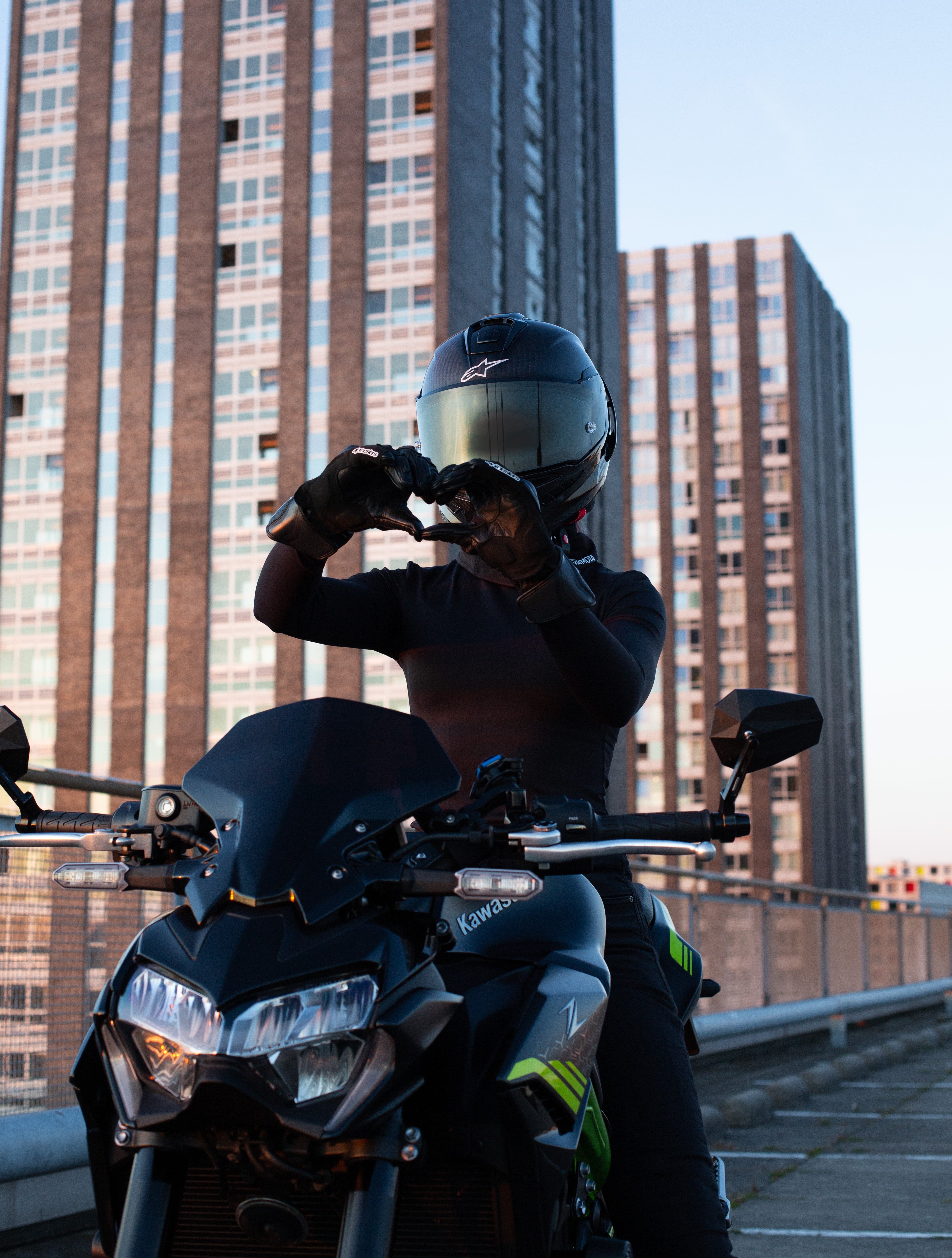 Female motorcycle rider wearing BRAIDFIT BALACLAVA making heart gesture